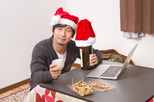 クリスマスにこたつでひとりグラスを傾けて晩酌する男性