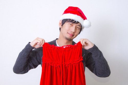 サンタの女性用コスプレのスカートを手にして苦笑いする男性