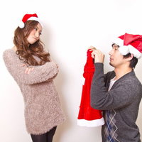 彼女にサンタの衣装を着てほしいと手を合わせてお願いする男性の写真