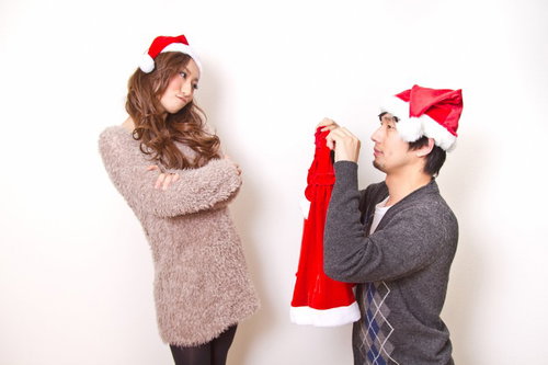 彼女にサンタの衣装を着てほしいと手を合わせてお願いする男性