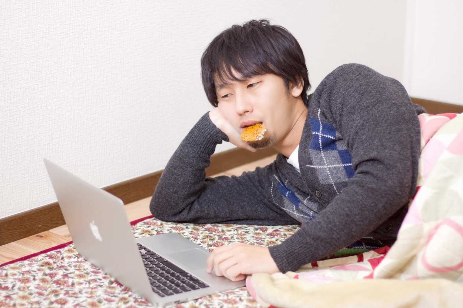 こたつで寝転んでPC操作する男性［モデル：大川竜弥］