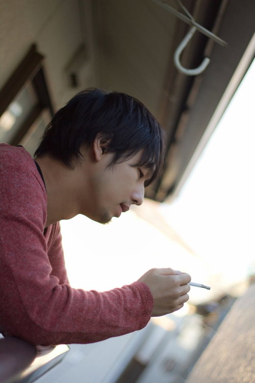 夜のベランダの柵越しに煙草の煙が漂う喫煙風景