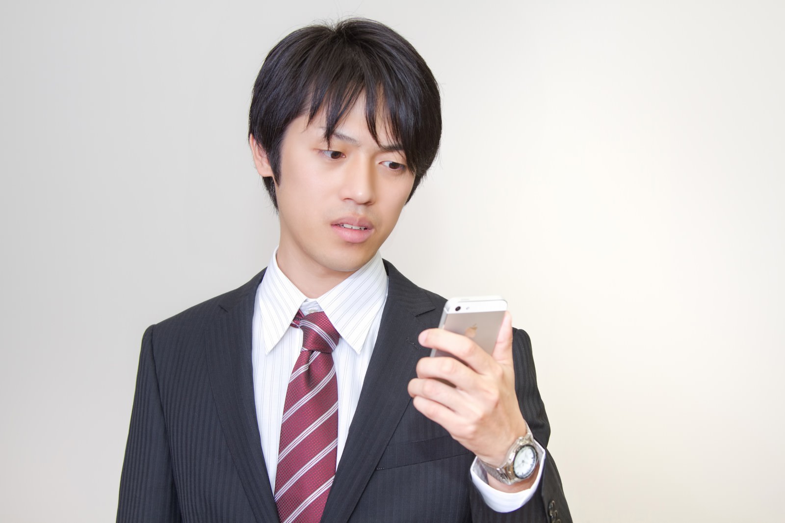 スマホの画面に驚くサラリーマン［モデル：Tsuyoshi.］