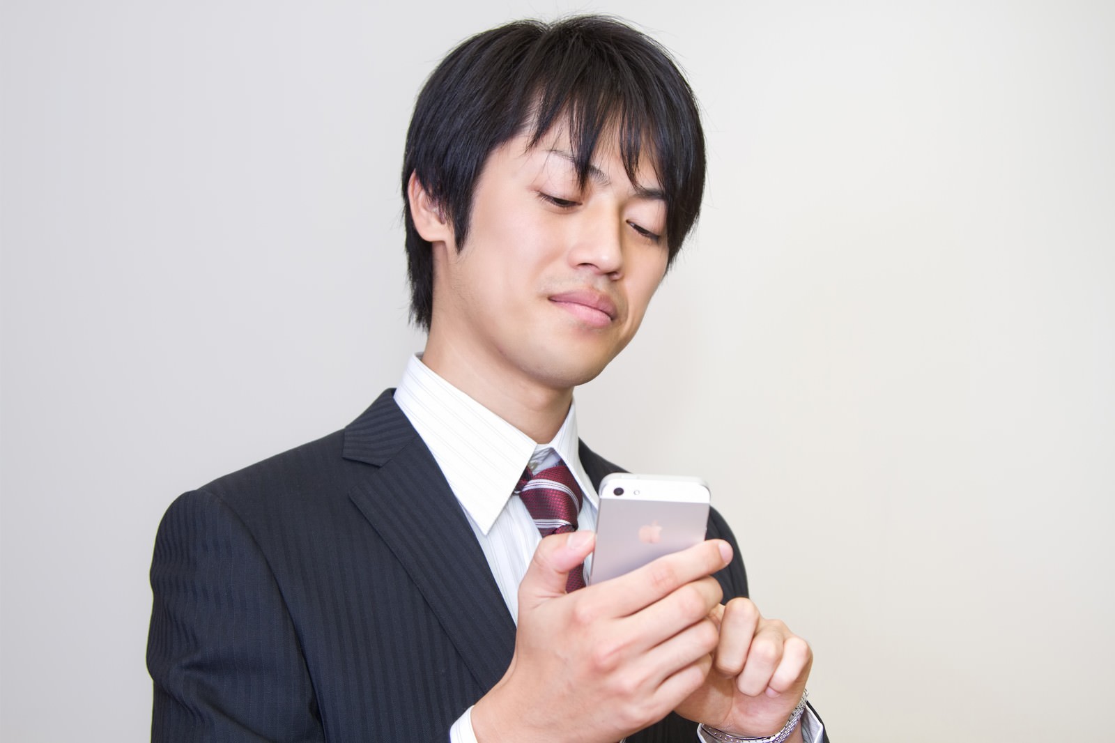 ニヤニヤしてスマホを見るサラリーマン［モデル：Tsuyoshi.］