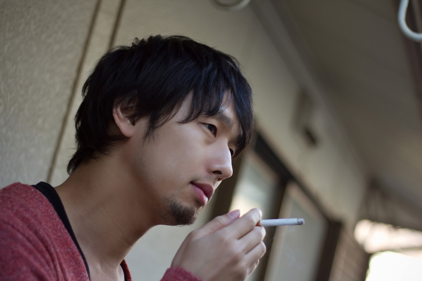 夜のベランダで煙草を吸う男性［モデル：大川竜弥］