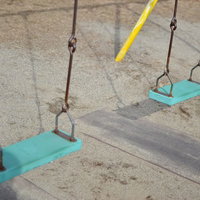 誰もいない静かな公園に等間隔で吊られたブランコの写真