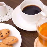 コーヒーカップとクッキーとミルクピッチャーが並ぶカフェ風景の写真