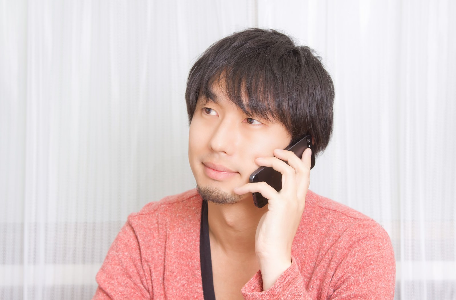 笑顔で彼女に電話する男性［モデル：大川竜弥］