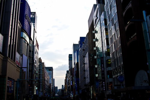 夕方のオレンジの空の下でネオンが灯り始める銀座