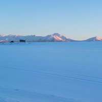夕焼けのオレンジに染まる北海道の十勝岳の山並みの写真