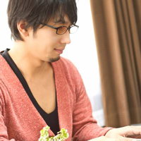 色眼鏡をかけてノートPCのキーボードを叩くカジュアルな男性の写真