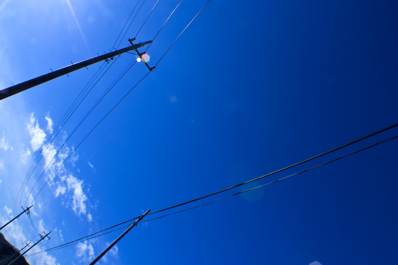 青空に電線が伸びる電柱