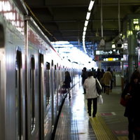 ホームに電車が停車し乗降客がいる駅のプラットフォームの写真