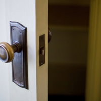 薄暗い部屋で半開きになったドアの向こうに光が差すの写真