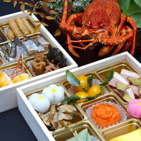 赤い伊勢海老が飾られた豪華なおせち料理の重箱の写真