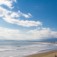冬の灰色の空を背景に波が打ち寄せる江ノ島の海の写真