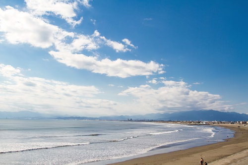 冬の灰色の空を背景に波が打ち寄せる江ノ島の海