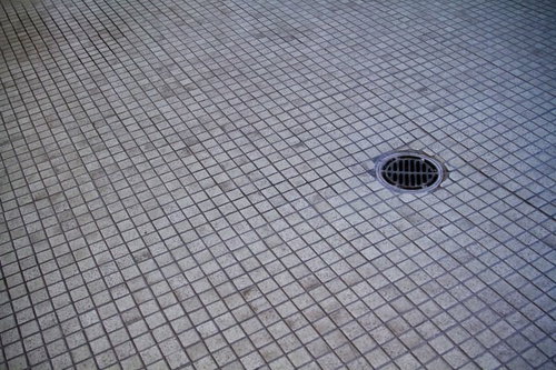 黒ずんだ汚れが染みついたタイルの床と排水口