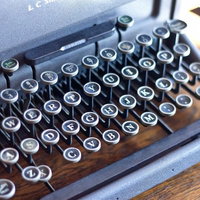 表面にうっすら埃が積もった古いタイプライターの正面の写真