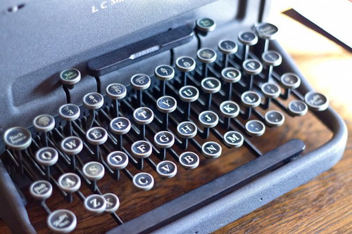 表面にうっすら埃が積もった古いタイプライターの正面