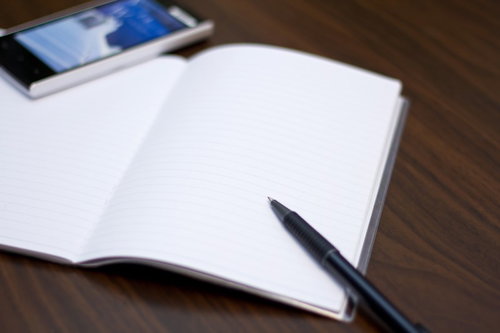 机の上に並べた携帯電話とノートとペンのビジネスセット