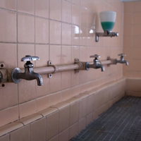 蛇口が錆びて壁が朽ちた使われなくなった手洗い場の写真