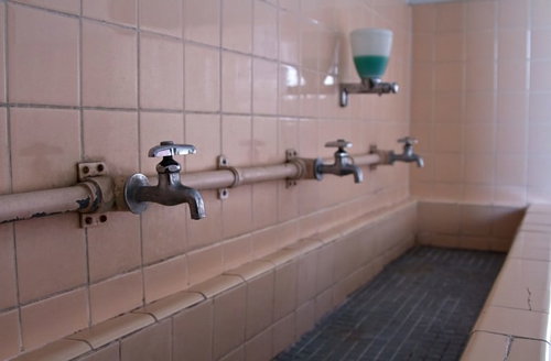 蛇口が錆びて壁が朽ちた使われなくなった手洗い場