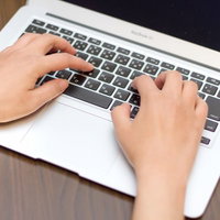 MacBook Airのキーボードの上でタイピングする指の接写の写真