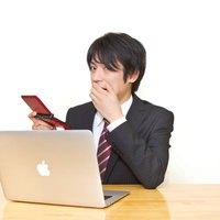 仕事中にデスクでこっそりゲームをして上司に見つかった男性の写真