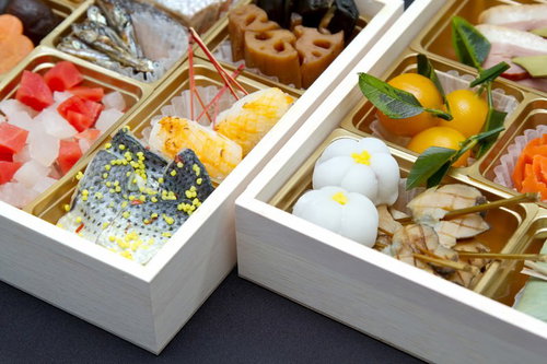 桐の木箱に色とりどりのおかずが詰められたおせち料理