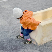公園の滑り台を笑顔で降りてくる子供の写真