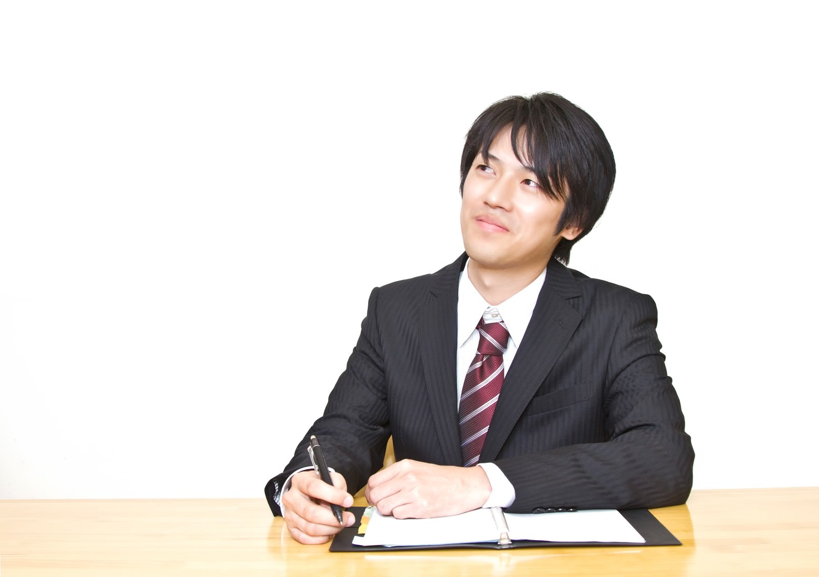 手帳を確認するスーツの男性［モデル：Tsuyoshi.］