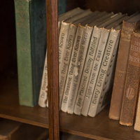 木の本棚に背表紙が並ぶ洋書のコレクションの写真