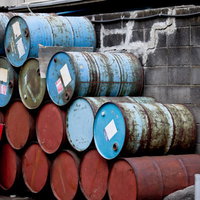 屋外に積み重ねられた錆びた古いドラム缶の写真