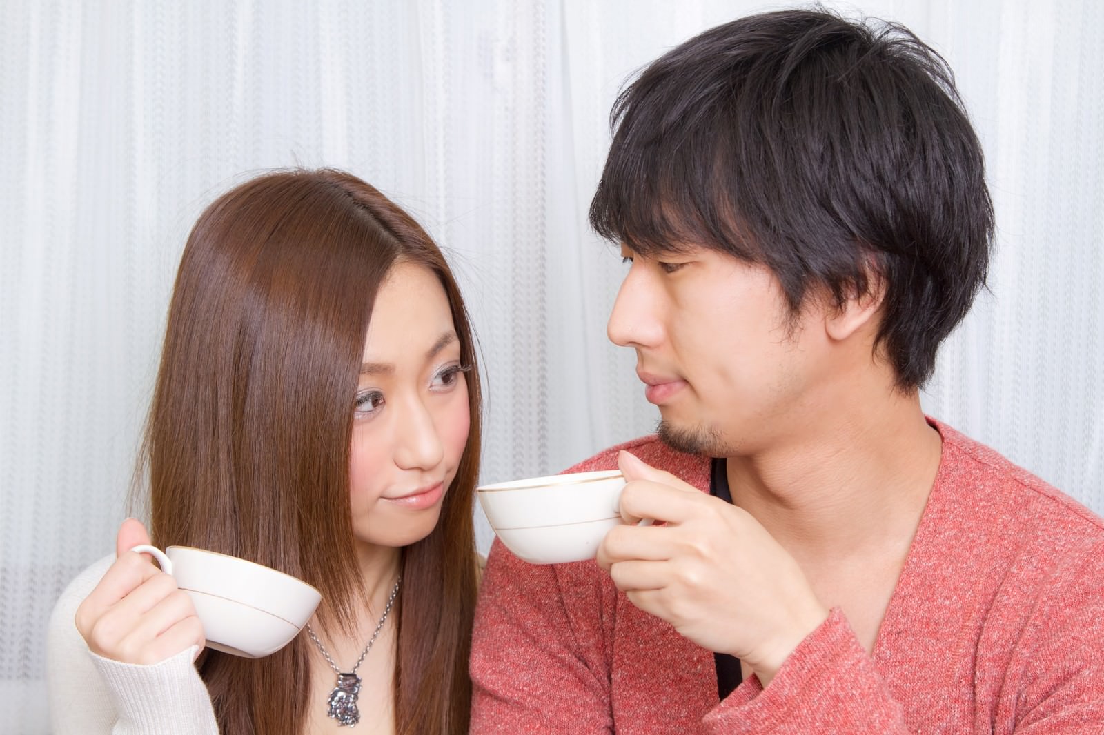 コーヒーを持って見つめ合う恋人［モデル：大川竜弥 北野佑々］