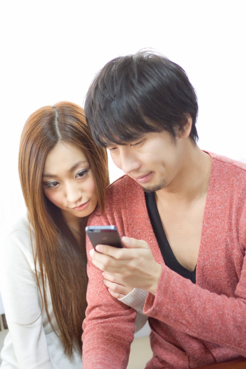 スマホを一緒に覗いて楽しむ恋人［モデル：大川竜弥 北野佑々］