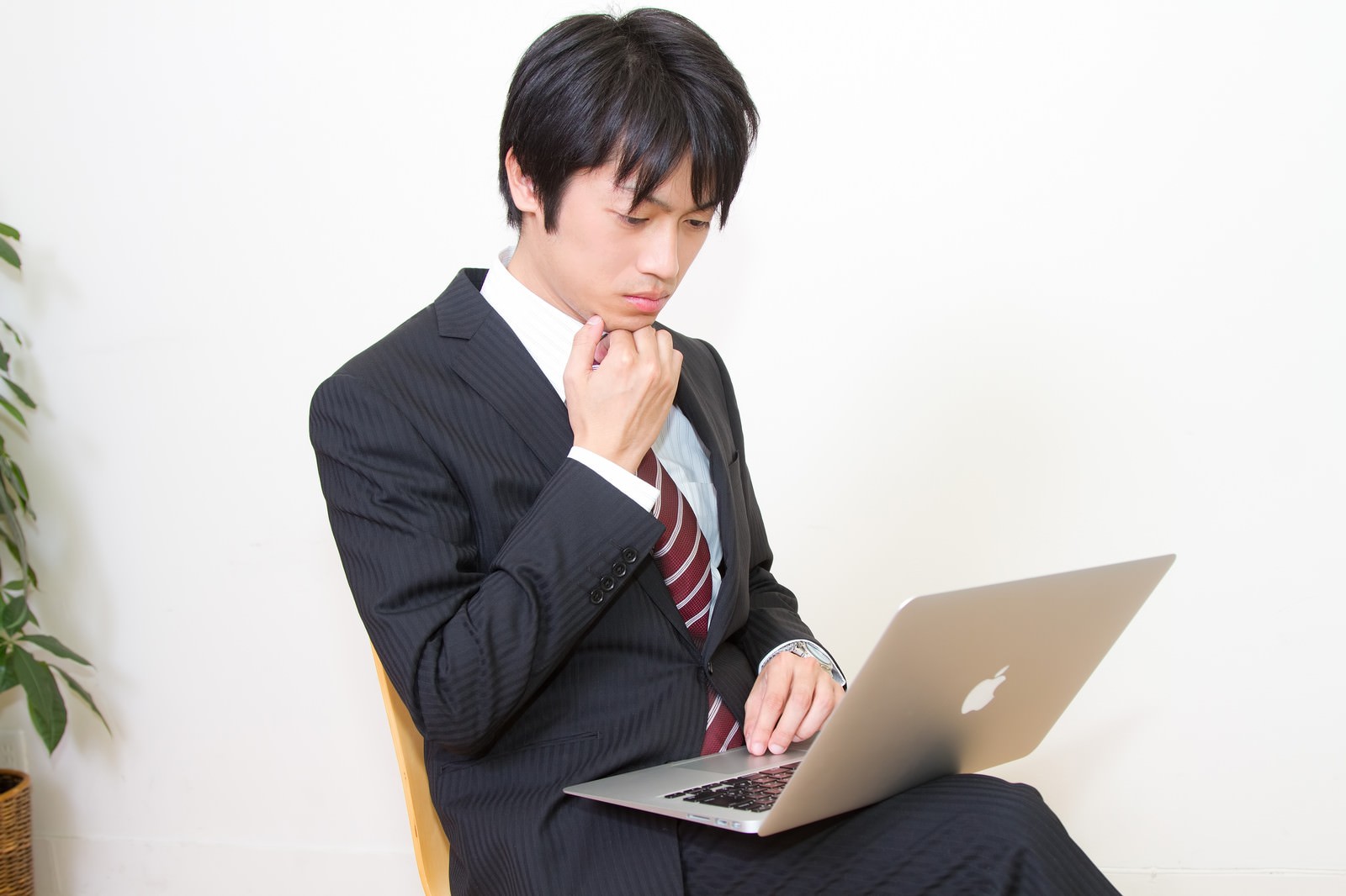 MBAを膝に置きあごに手を当てて考える男性［モデル：Tsuyoshi.］