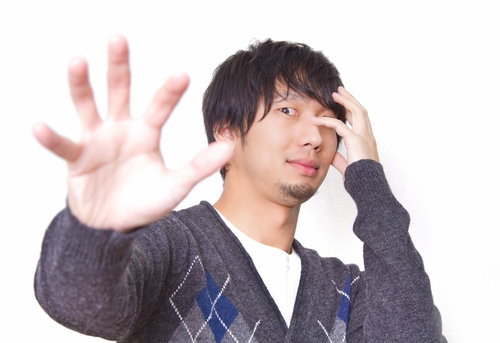 片目を手で隠して「俺の邪気眼が...」と中二病ポーズをする男性