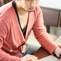 モニターを見ながらPCのキーボードを操作しチェックする男性の写真