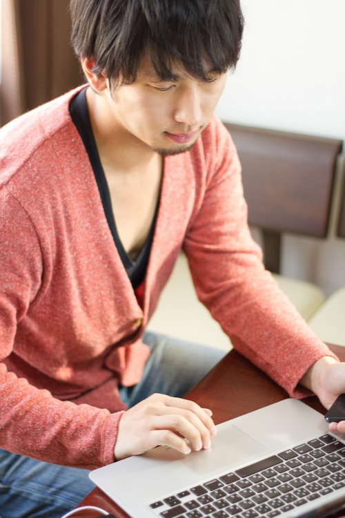 モニターを見ながらPCのキーボードを操作しチェックする男性