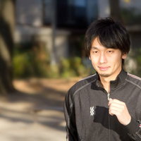 公園の道をジャージ姿でランニングする男性の横姿の写真