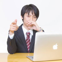 水色の壁の前で指を立てて提案を指摘するビジネスマンの写真