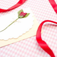 赤いリボンが結ばれた封筒と白い手紙のレターセットの写真