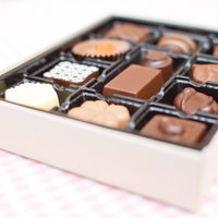 赤いリボンが結ばれた箱に入ったバレンタインのチョコレートの写真