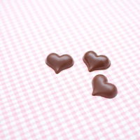ピンクのランチョンマットの上に置かれたハート型チョコレートの写真