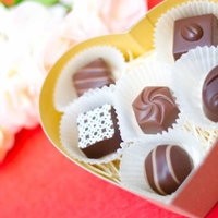 ハート型の赤い箱とその中に詰まったチョコレートのギフトの写真