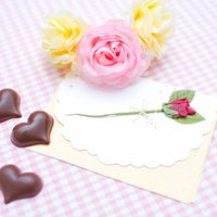 赤いバラの造花と封筒の手紙にハート型チョコが添えられたバレンタインセットの写真