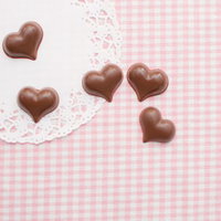 ピンクのストライプ柄の上に並ぶハート型チョコレートの写真