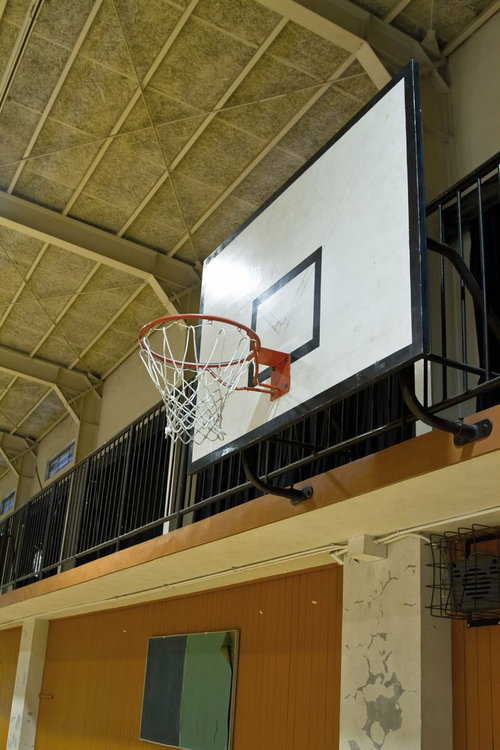 天井の照明に照らされた体育館のバスケットゴールの見上げ