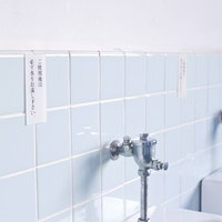 白いタイルの壁と小便器が並ぶ学校の男子トイレの写真